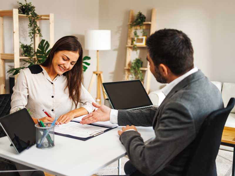 Happy woman signing loan documents.